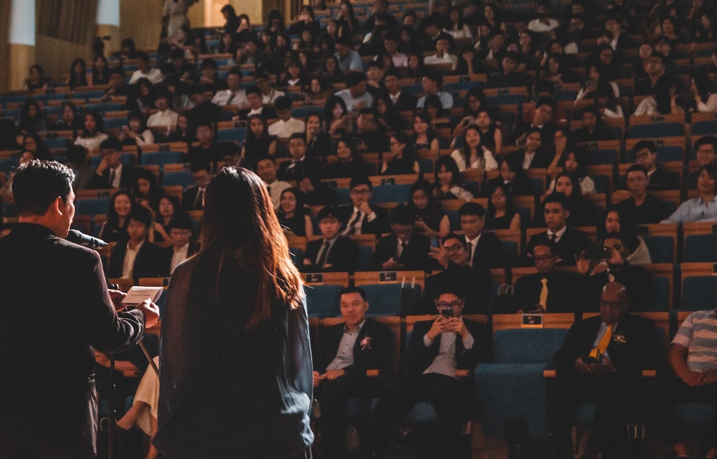 Stock photo of man and woman at podium speaking in front of audience